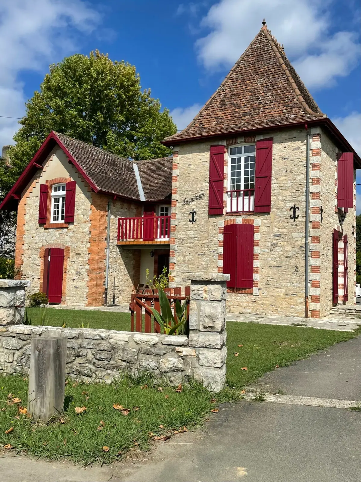 Una casa de piedra con contraventanas rojas, cerrada